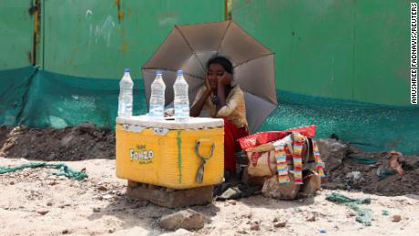 Ein Mädchen, das Wasser verkauft, benutzt einen Regenschirm, um sich während einer Hitzewelle in Neu-Delhi, Indien, vor der Sonne zu schützen.