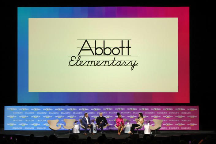 Kenta Bronson in einem rosa Anzug spricht während einer Podiumsdiskussion über die Abbott Elementary School.