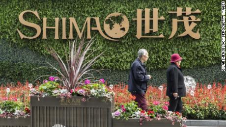 Ein älteres Ehepaar läuft vor einem Schild vor dem Shimao Tower, der von Shimao Group Holdings Ltd. entwickelt wurde.  , in Shanghai, China, am Samstag, den 8. Januar 2022. 